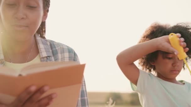 Uma Bela Mãe Afro Americana Está Lendo Livro Enquanto Seus — Vídeo de Stock