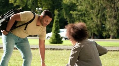 Bir çift öğrenci erkek ve kadın dışarıda çimlerin üzerinde oturacaklar.