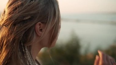 Güzel bir kadın doğaya doğru yürürken uzaklara bakar.