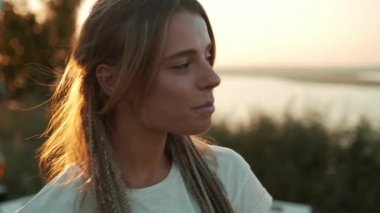 Dışarıda karavanın yanında kameraya bakan mutlu bir kadın var.