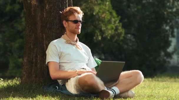 Hombre Concentrado Con Gafas Está Usando Portátil Sentado Hierba Afuera — Vídeo de stock