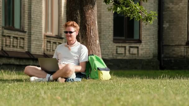 Szczęśliwy Student Używa Laptopa Siedząc Trawie Kampusie Zewnątrz — Wideo stockowe