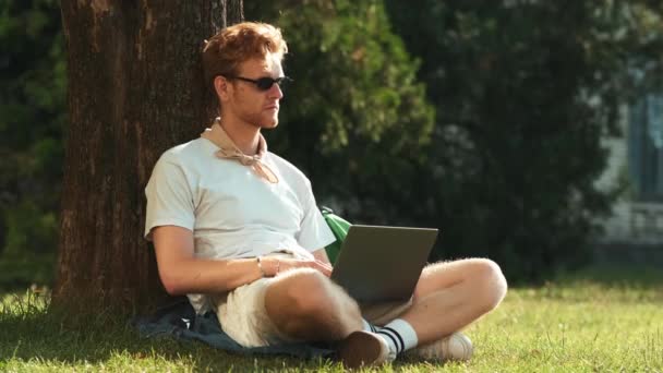 Student Okularach Używa Laptopa Siedząc Trawie Zewnątrz — Wideo stockowe