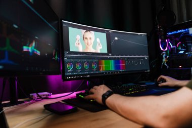 Beyaz bir adamın arka plan görüntüsü büyük bir ekranın önünde oturan video düzenleyicisi kapalı alanda bir video montajı üzerinde çalışıyor.