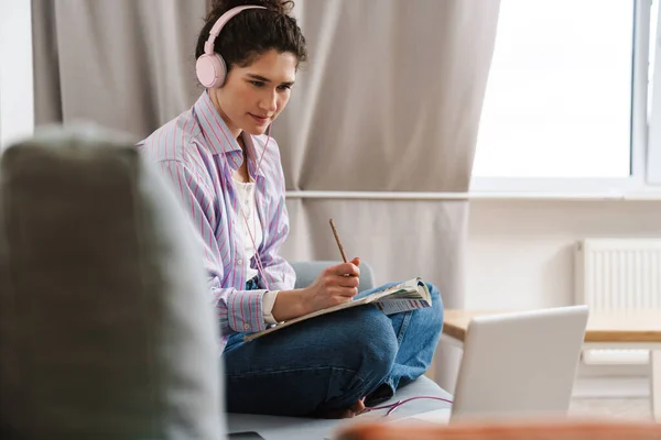 Πορτρέτο Μιας Μέσης Νεαρής Γυναίκας Ακουστικά Που Διαβάζει Ενώ Κάθεται — Φωτογραφία Αρχείου