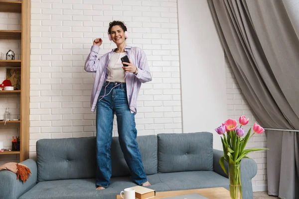 Mujer Morena Joven Feliz Escuchando Música Con Auriculares Bailando Sofá — Foto de Stock