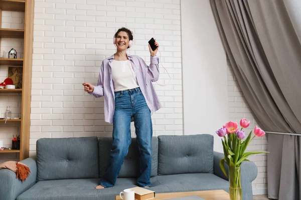 Happy Young Brunette Woman Listening Music Headphones Dancing Couch — Stock Photo, Image