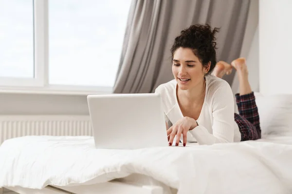 Donna Dattilografa Positiva Sdraiata Pigiama Sul Letto Una Stanza Luminosa — Foto Stock