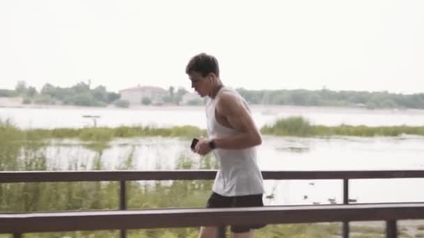 Bir Atlet Dışarıda Parkta Cep Telefonundan Müzik Dinlerken Koşuyor — Stok video