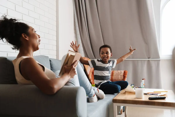 Negro Alegre Mujer Leyendo Libro Divertirse Con Hijo Casa — Foto de Stock