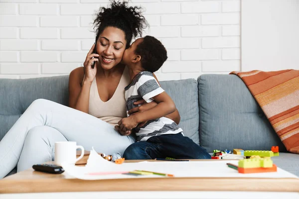 Mujer Negra Sonriente Hablando Por Celular Mientras Abraza Hijo Casa — Foto de Stock