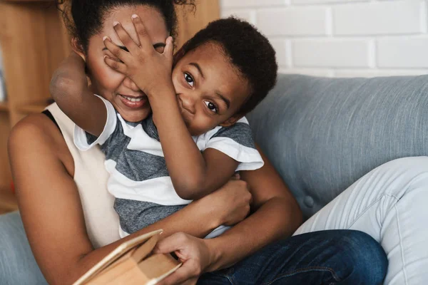 Negro Sonriente Madre Hijo Burlándose Leyendo Libro Sofá Casa — Foto de Stock