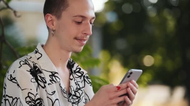 一位戴耳环的快乐嬉皮士站在外面用手机拍照 — 图库视频影像