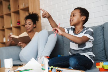 Siyahi kadın kitap okurken oğlu evlerini işaret ediyor.