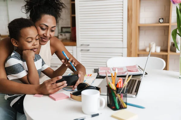 Nero Madre Figlio Utilizzando Telefono Cellulare Mentre Seduti Insieme Casa — Foto Stock