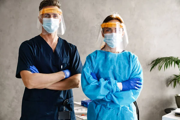 Dos Doctores Con Uniforme Médico Protector Pie Gabinete Brazos Cruzados —  Fotos de Stock