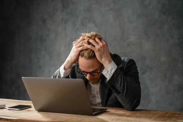 Homem Sentado Mesa Frente Laptop Enquanto Aperta Cabeça Estúdio — Fotografia de Stock