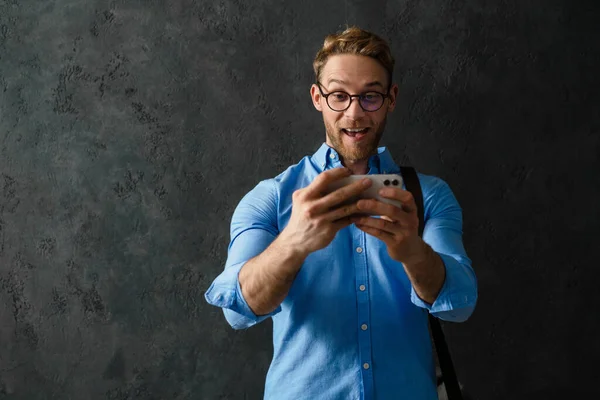 Hombre Sonriente Con Una Camisa Azul Gafas Mirando Teléfono Mientras — Foto de Stock