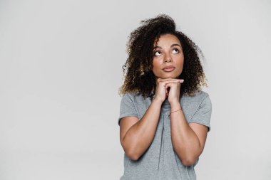 Düşünceli bir kadın, ışık stüdyosunda dikilirken ellerini yukarı kaldırdı.