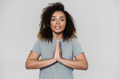 Kıvırcık saçlı kadın ışık stüdyosunda dururken avuç içiyle bir şey istiyor.