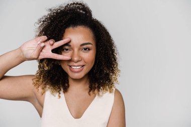 Gülümseyen bir kadının portresi. Stüdyoda dururken barış jesti yapıyor ve gözünün önünde el ele tutuşuyor.