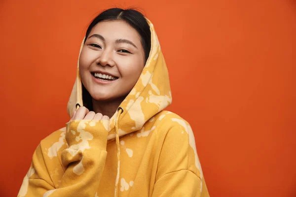 후드를 아시아 소녀가 웃으며 주황색 배경에서 고립된 카메라를 — 스톡 사진
