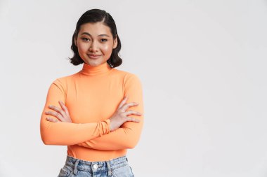 Genç Asyalı esmer kadın gülümsüyor ve beyaz arka planda izole edilmiş kameraya bakıyor.