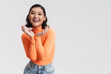 Genç Asyalı esmer kadın gülümsüyor ve elinde telif alanı tutuyor. Beyaz arka planda izole edilmiş.