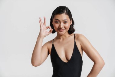 Mayo giymiş esmer bir kadın gülümsüyor ve beyaz arka planda 