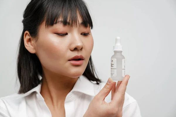 Jovem Mulher Asiática Posando Enquanto Mostra Soro Facial Isolado Sobre — Fotografia de Stock