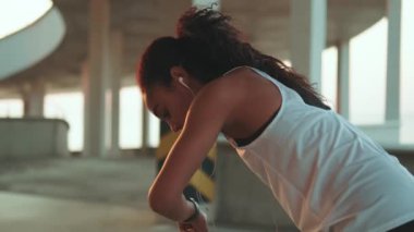 Sabahları kulaklık takan Afro-Amerikalı bir kadın koşuyor.