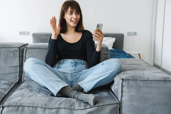 Smiling Young Woman Using Mobile Phone While Sitting Couch Home — Stock Photo, Image