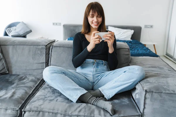 Lächelnde Junge Frau Mit Handy Während Sie Hause Auf Der — Stockfoto