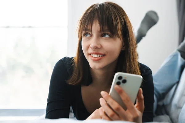 Усміхнена Молода Жінка Використовує Мобільний Телефон Лежачи Дивані Вдома — стокове фото