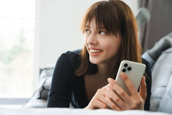 Glimlachende Jonge Vrouw Die Mobiele Telefoon Sms Terwijl Thuis Bank — Stockfoto