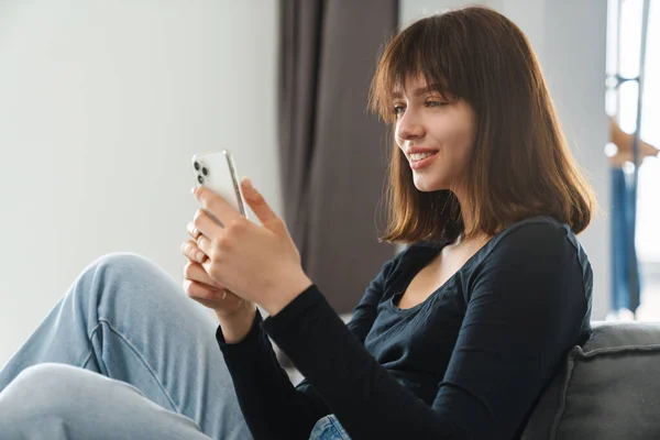 Sorrindo Jovem Segurando Mensagens Texto Telefone Celular Enquanto Sentado Encostado — Fotografia de Stock