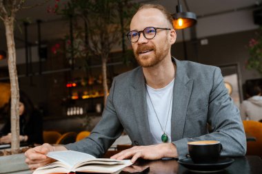 Kafede kapalı bir yerde oturup yazı yazarken kendinden emin orta yaşlı beyaz iş adamı