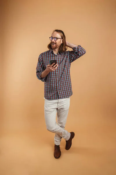 White Ginger Man Wearing Eyeglasses Smiling Using Cellphone Isolated Beige — Stock Photo, Image