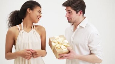 Bir adam stüdyoda beyaz bir arka planda duran kız arkadaşına güzel bir hediye sunuyor.