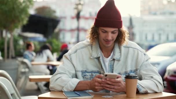 Hombre Complacido Con Chaqueta Vaquera Usando Móvil Sentado Terraza Cafetería — Vídeos de Stock