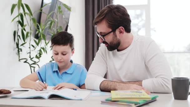 Vader Helpt Zijn Zoon Met Huiswerk Thuis Zitten — Stockvideo
