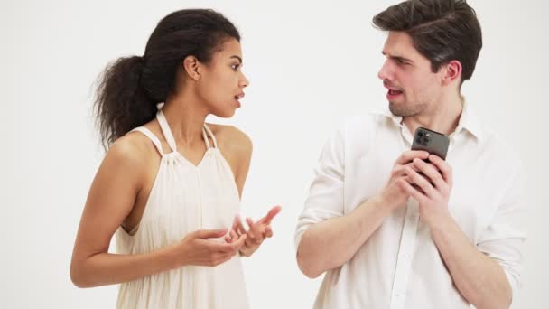 男人不会在手机上对他的女朋友表现出满足 因为他在工作室里的背景是白色的而孤立无援 — 图库视频影像
