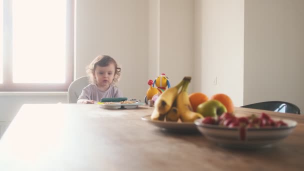 Een Prachtige Baby Zit Kinderstoel Kijkt Mobiel Keuken Thuis — Stockvideo