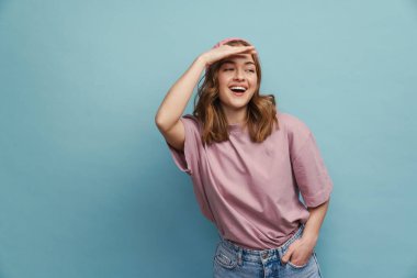 Gülümseyen ve yan bakan genç bir kadın. Mavi arka planda, yalnız başına, alnına bakıyor.