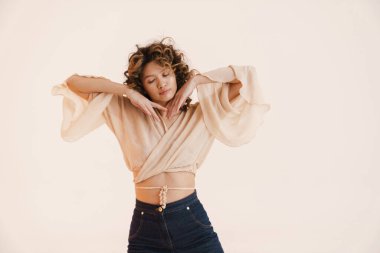 Beyaz arka planda dans eden kıvırcık saçlı genç İspanyol kadın.