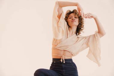 Beyaz arka planda dans eden kıvırcık saçlı genç İspanyol kadın.