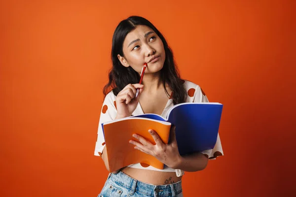 Pensive Jonge Aziatische Vrouw Student Staande Houden Leerboeken Rode Muur — Stockfoto