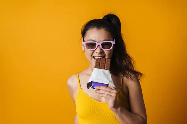 Щаслива Молода Азіатська Брюнетка Сонцезахисних Окулярах Тримає Шоколадний Батончик Стоїть — стокове фото
