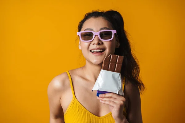 Щаслива Молода Азіатська Брюнетка Сонцезахисних Окулярах Тримає Шоколадний Батончик Стоїть — стокове фото