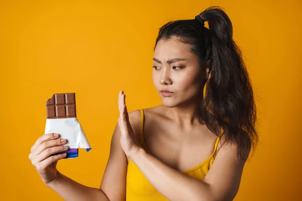 Портрет Засмученої Молодої Азіатки Тримає Шоколадний Батончик Стоїть Жовтому Тлі — стокове фото